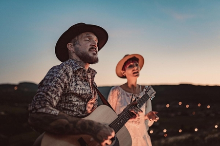 Un groupe de musique duo de Linkaband avec un guitariste et une chanteuse font un concert romantique dans un champ.
