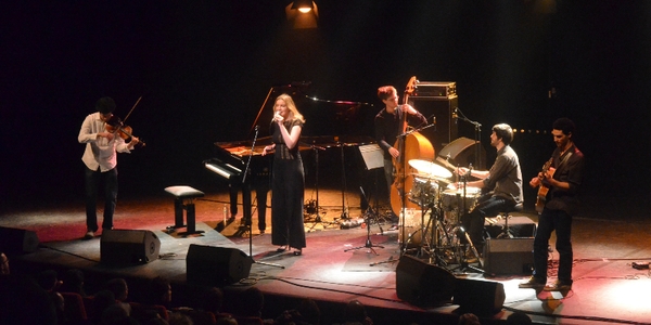 Une chanteuse et un guitariste sur scène animent un événement avec une prestation musicale.