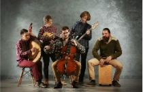 Orchestre composé d'un violoncelliste et de violonistes assis et jouant de leur instrument lors d'un concert.