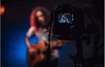 Vidéaste souriant tenant une caméra vidéo à la main avec un micro d'enregistrement et une lumière de tournage vidéo